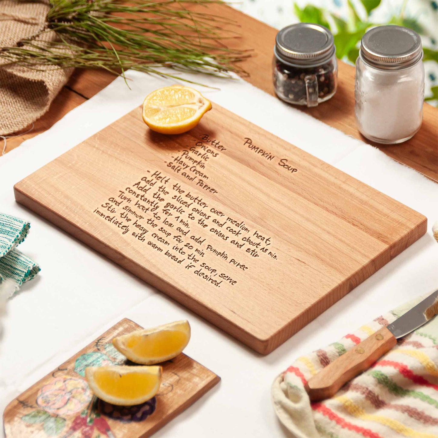 Wooden cutting board with engraved pumpkin soup recipe on a kitchen counter.