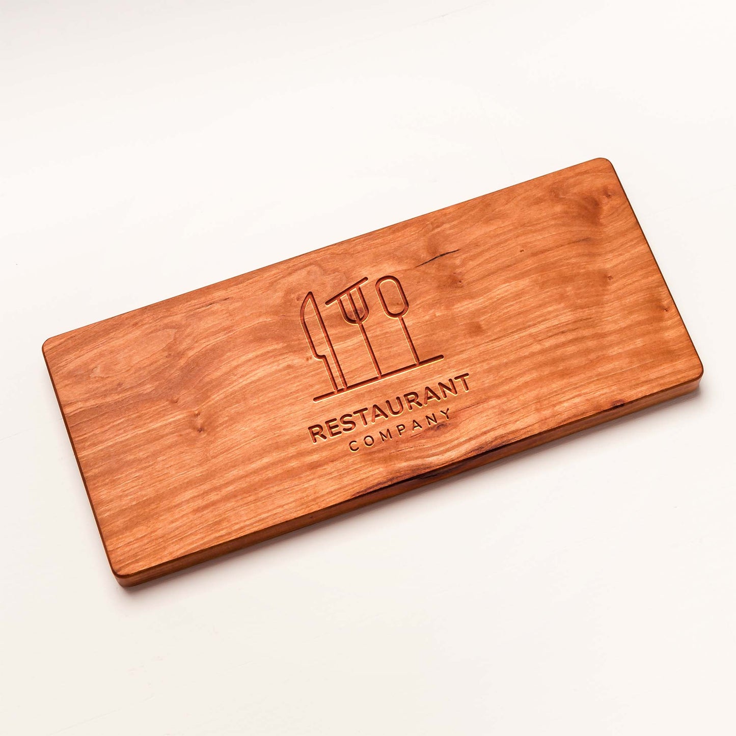 Wooden cutting board with engraved logo and text on a white background