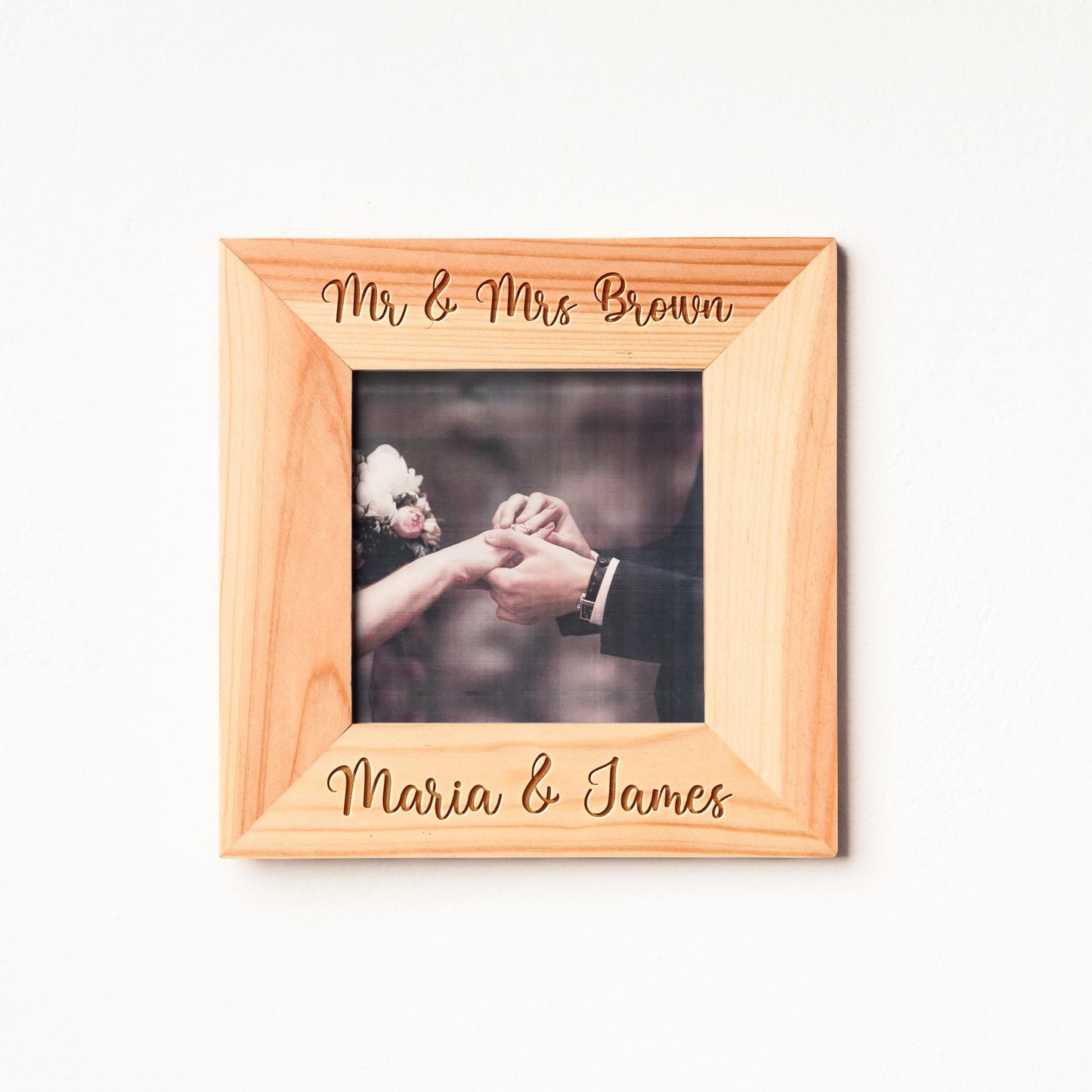 Personalized wooden square frame hanging on a rustic wall.
