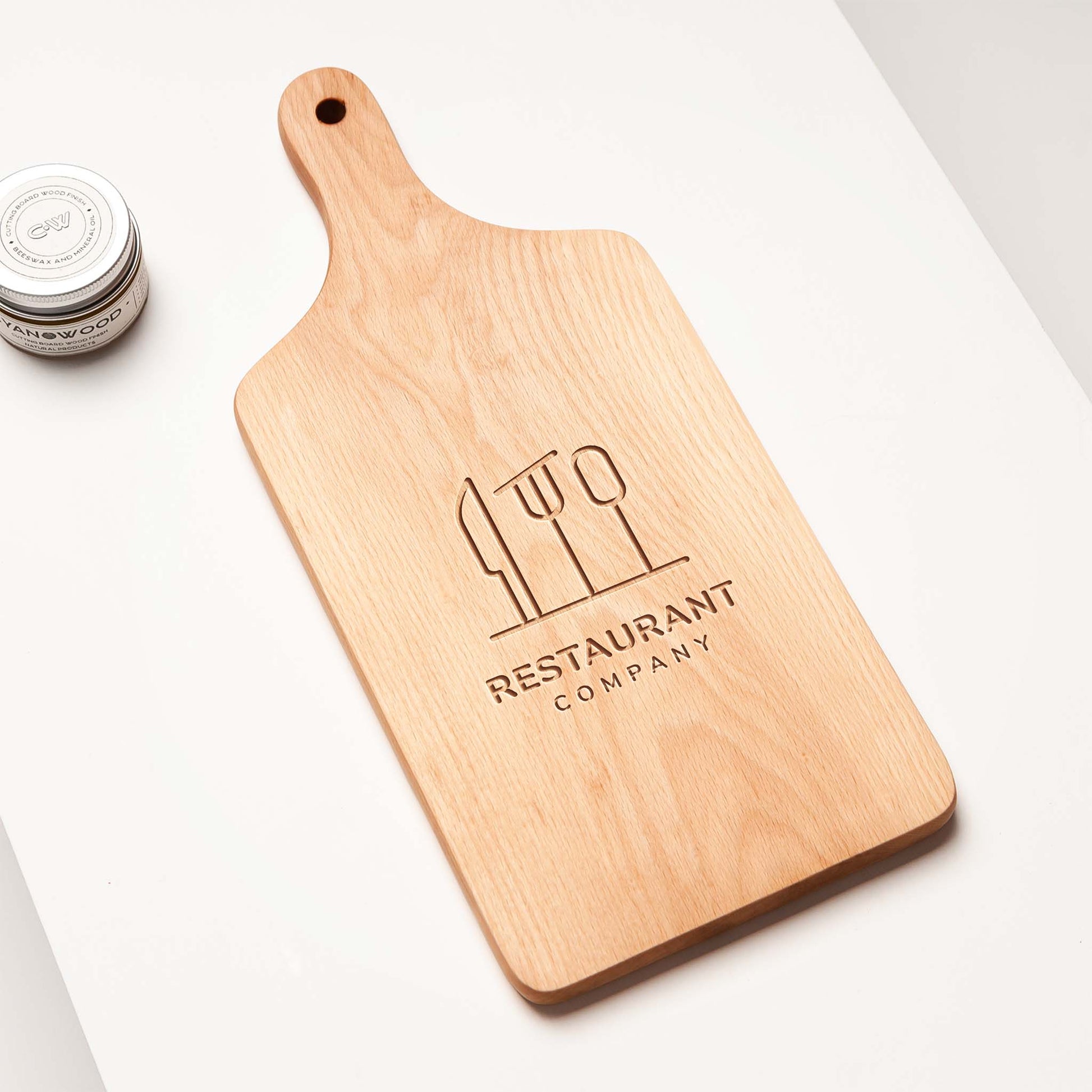 Wooden cutting board with engraved logo and text on a white surface