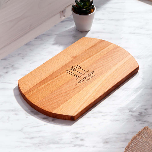Beech wood cutting board with rounded edges and engraved restaurant logo on marble surface — custom engraved wooden cutting board for restaurants and bars.