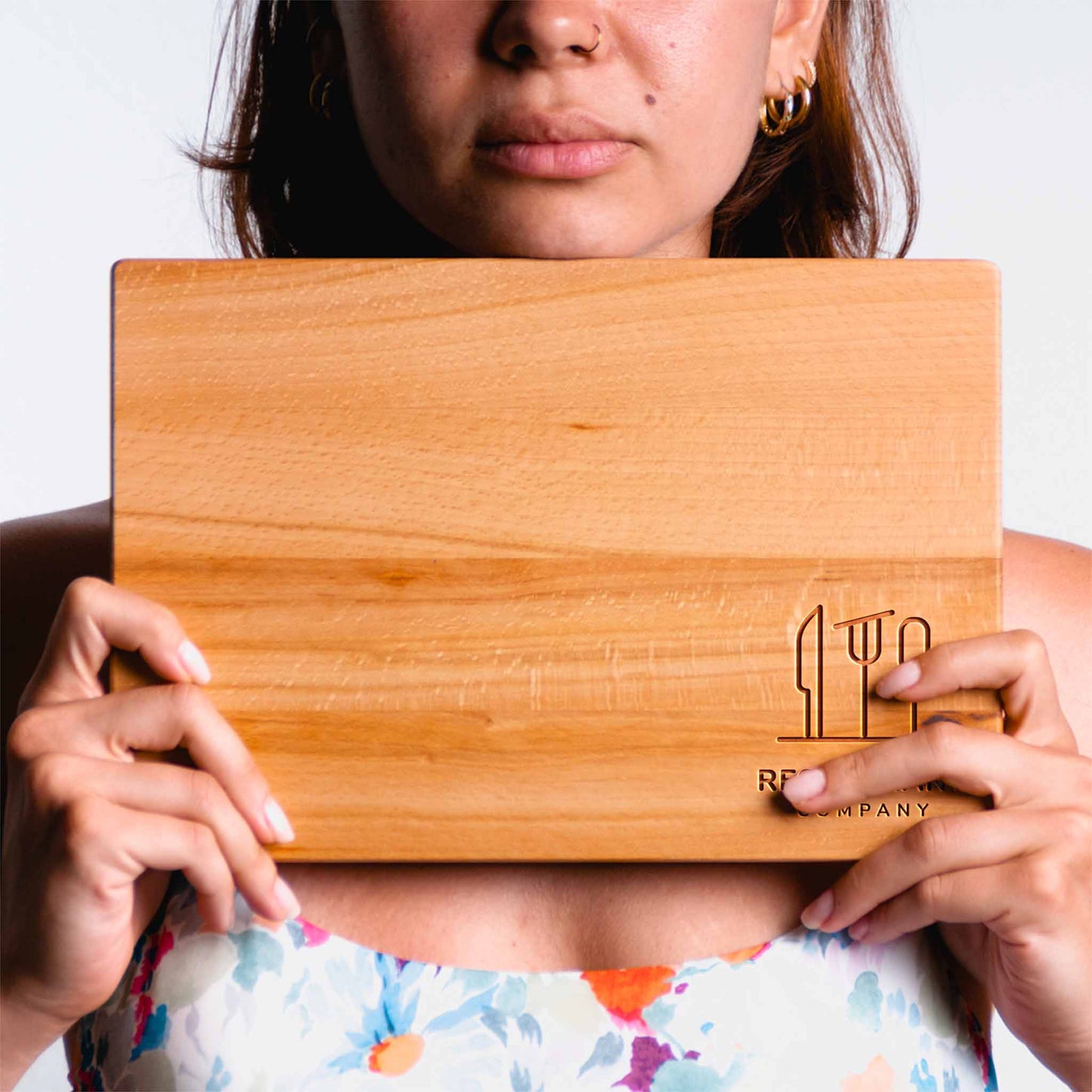 Person holding a wooden cutting board with a brand logo.