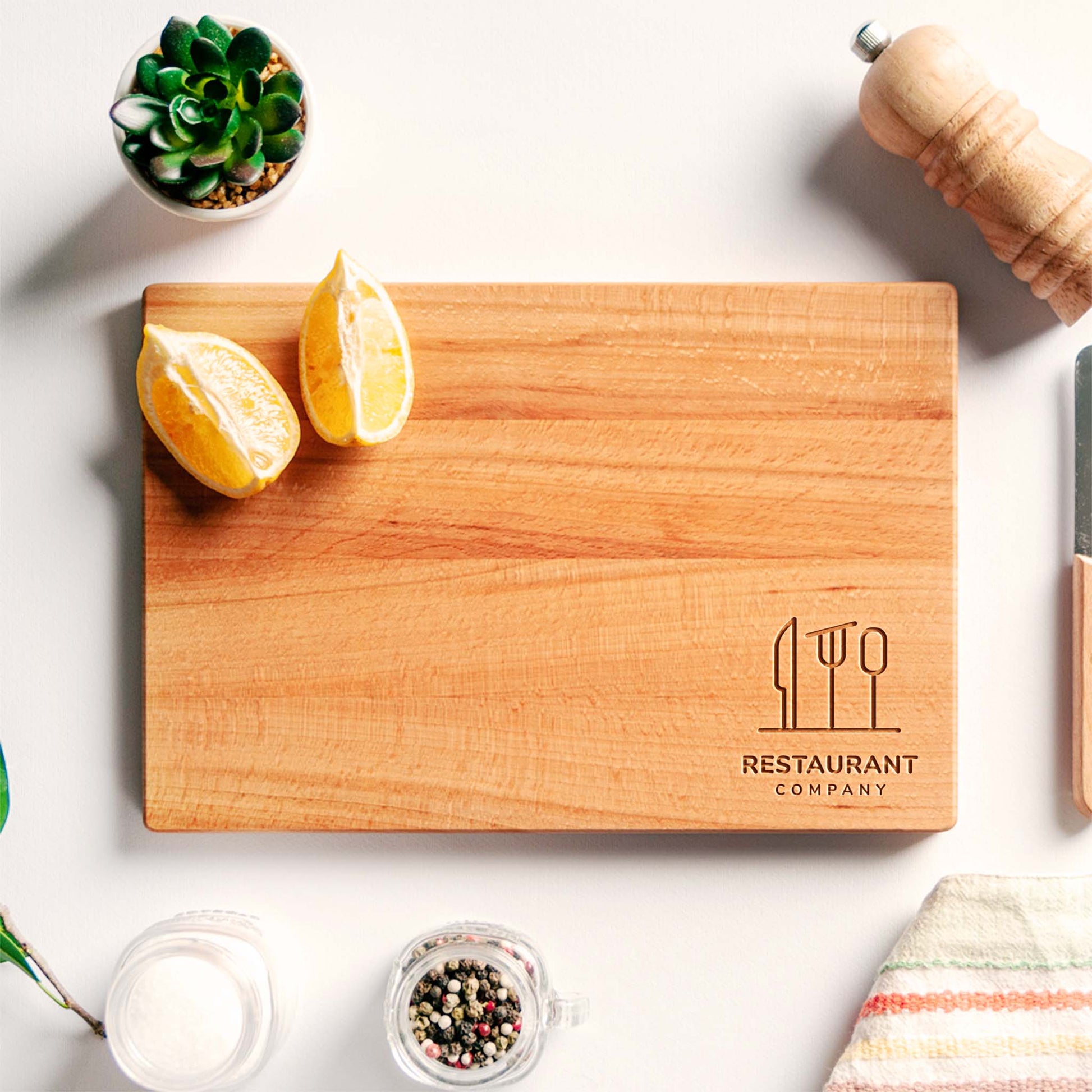 Wooden cutting board with 'Restaurant Company' branding on a white surface with lemons and a plant.