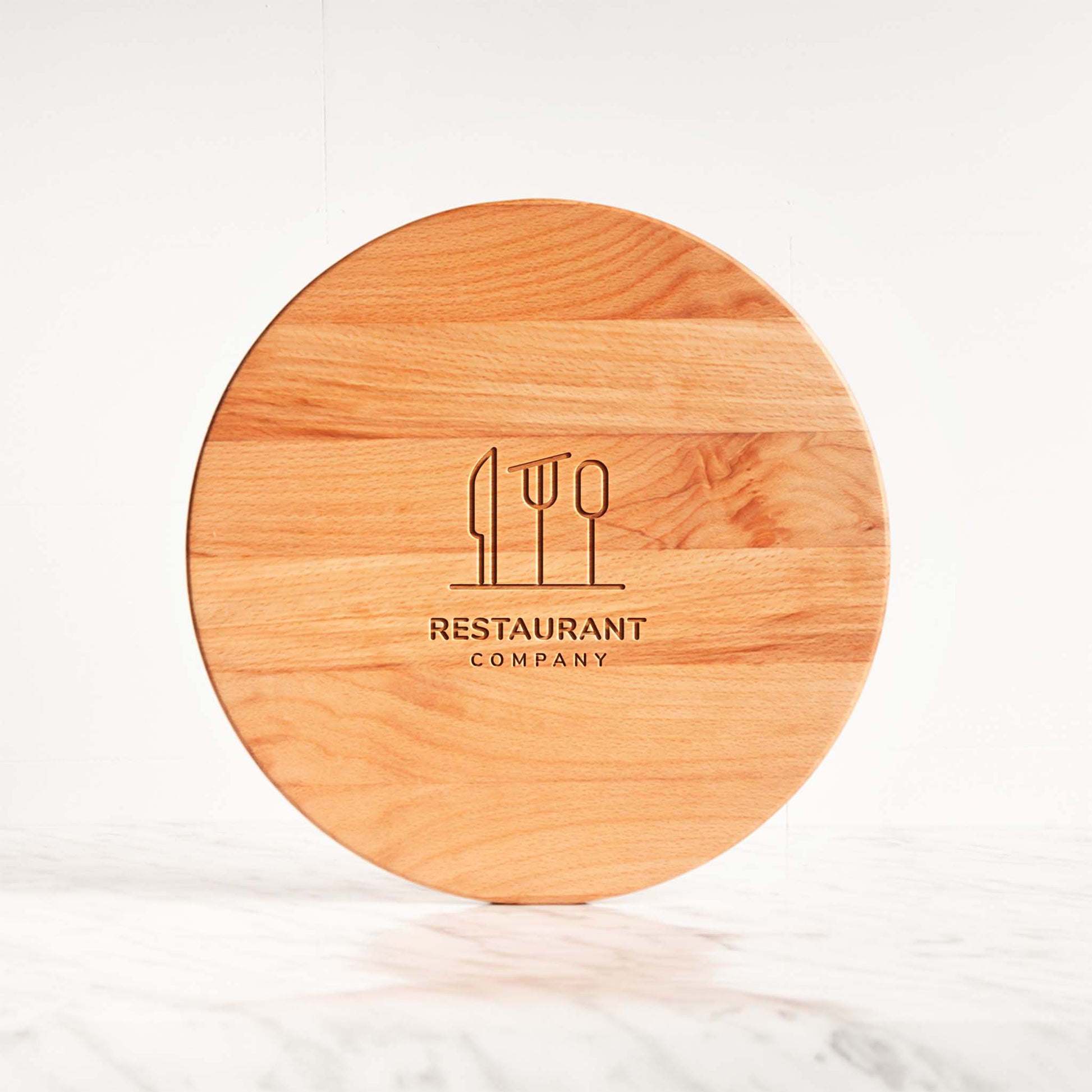 Round beech wood cutting board with restaurant logo engraving.