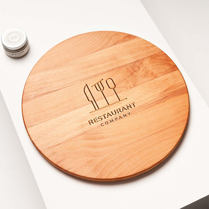 Wooden round cutting board with engraved 'Restaurant Company' logo on a white surface.