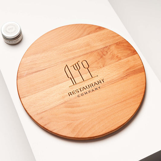 Wooden round cutting board with engraved 'Restaurant Company' logo on a white surface.