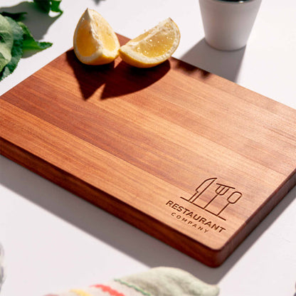 Wooden cutting board with 'Restaurant Company' logo on a light surface with lemon slices.