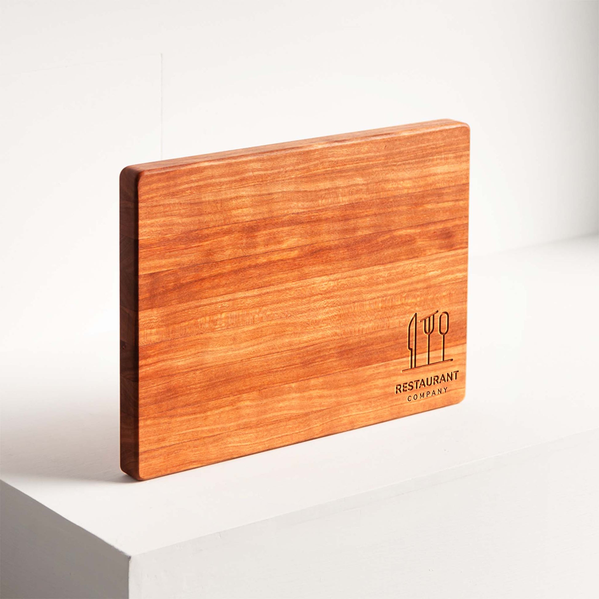 Wooden cutting board with engraved logo on a white surface