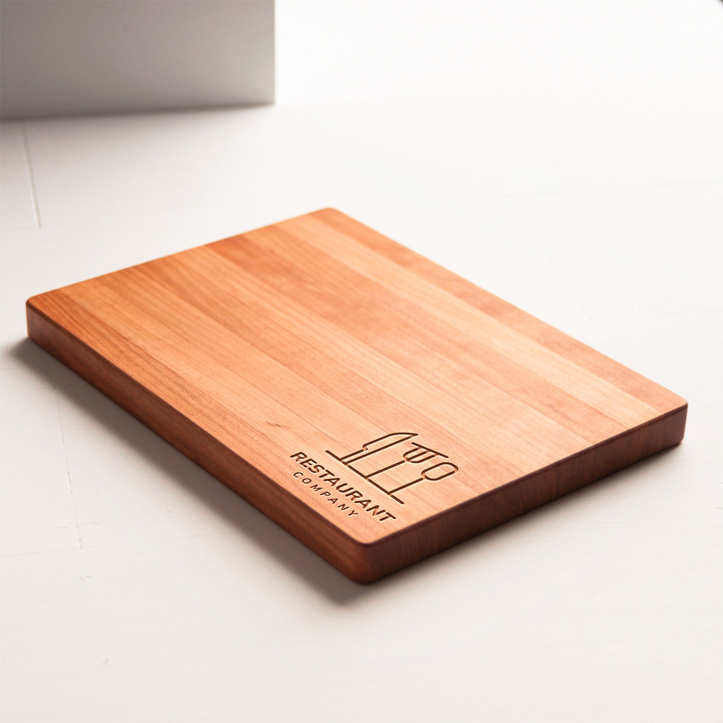 Wooden cutting board with engraved logo on a white surface