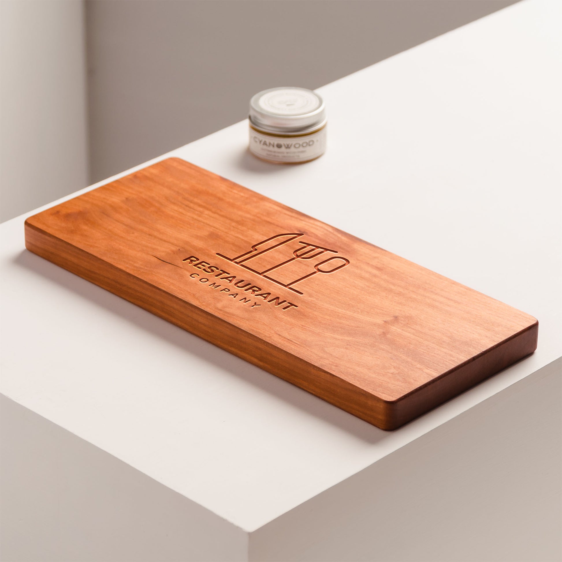 Wooden cutting board with 'Restaurant Company' logo on a white surface