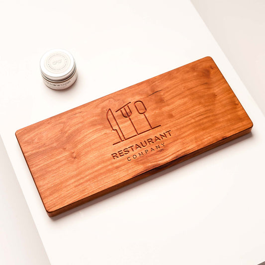 Wooden cutting board with engraved 'Restaurant Company' logo on a white surface