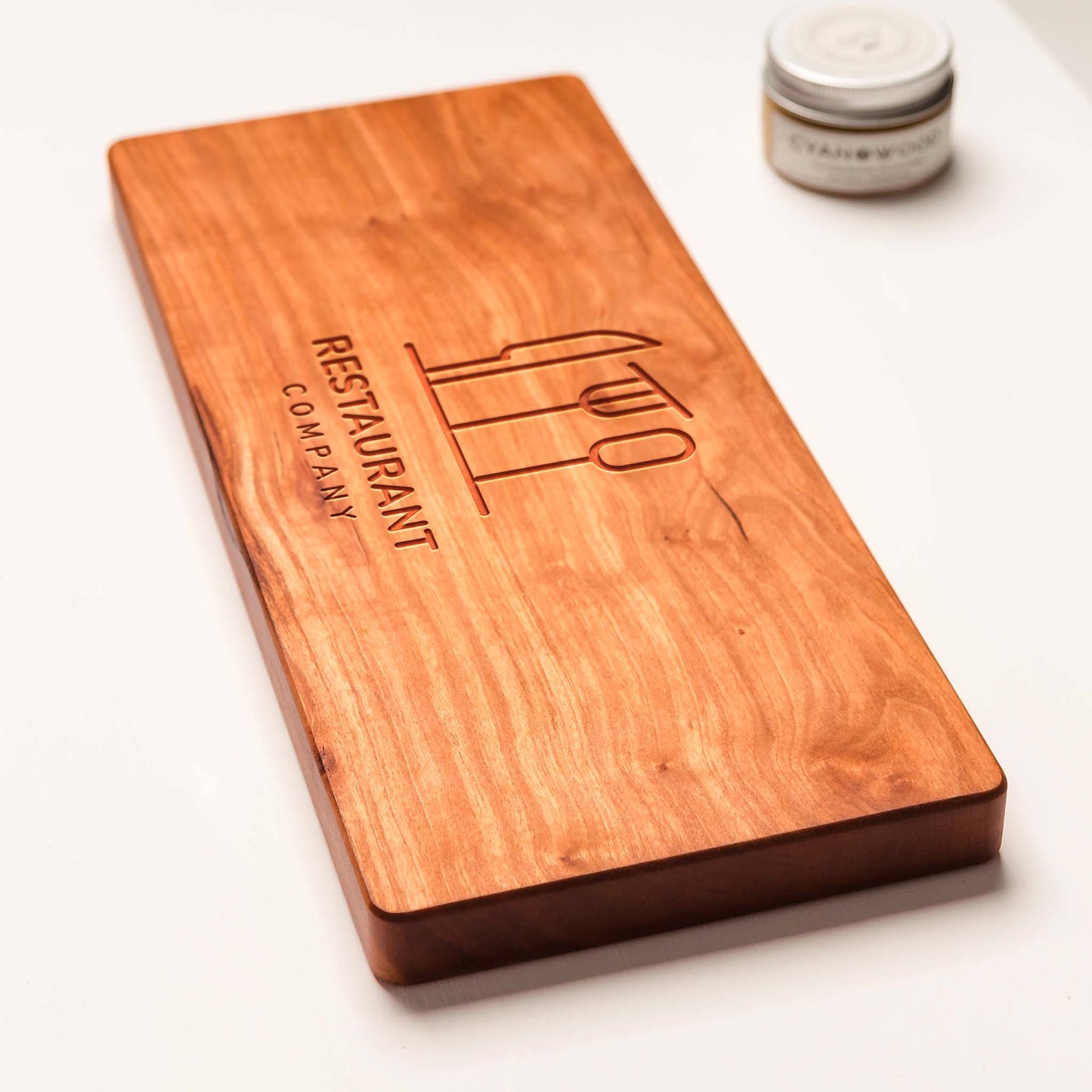 Wooden cutting board with engraved logo on a white background