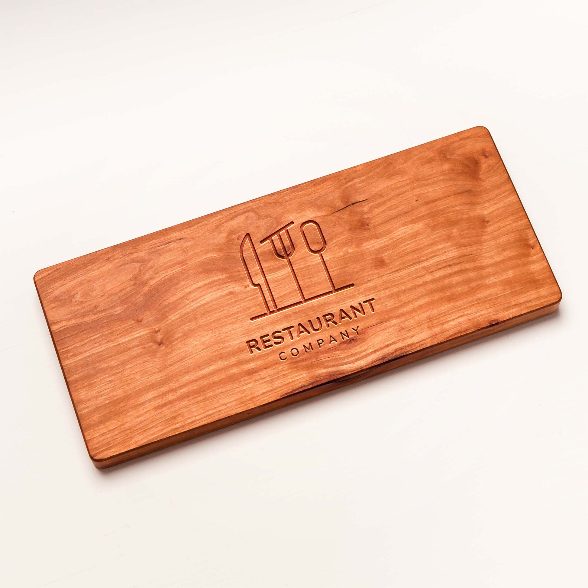 Wooden cutting board with engraved logo and text on a white background