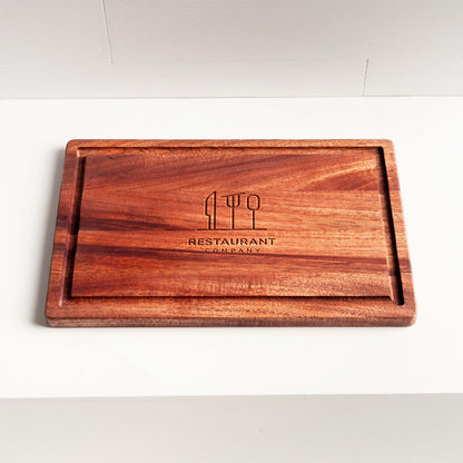Rectangular mahogany cutting board with juice groove and engraved restaurant logo.
