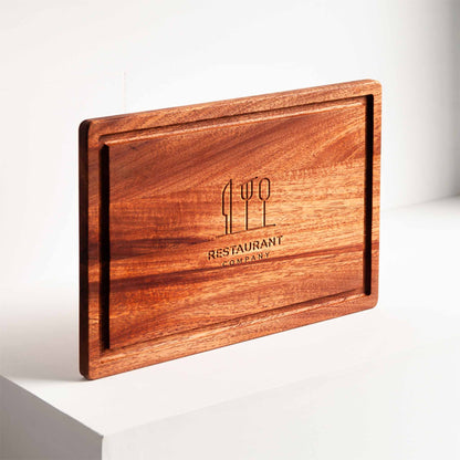 Rectangular mahogany cutting board with juice groove and engraved restaurant logo.