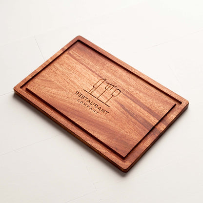 Rectangular mahogany cutting board with juice groove and engraved restaurant logo.