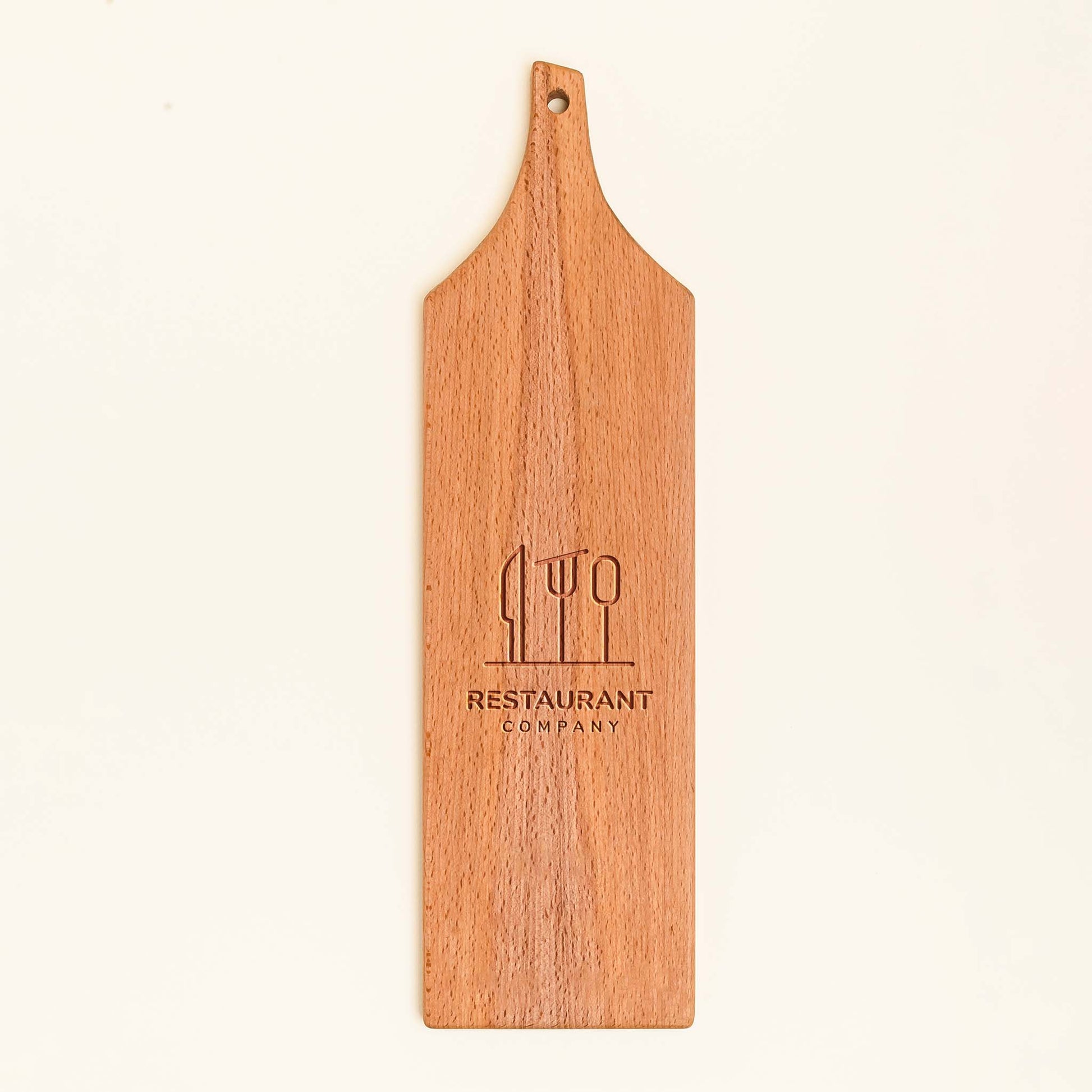 Wooden serving board with engraved logo and text on a beige background